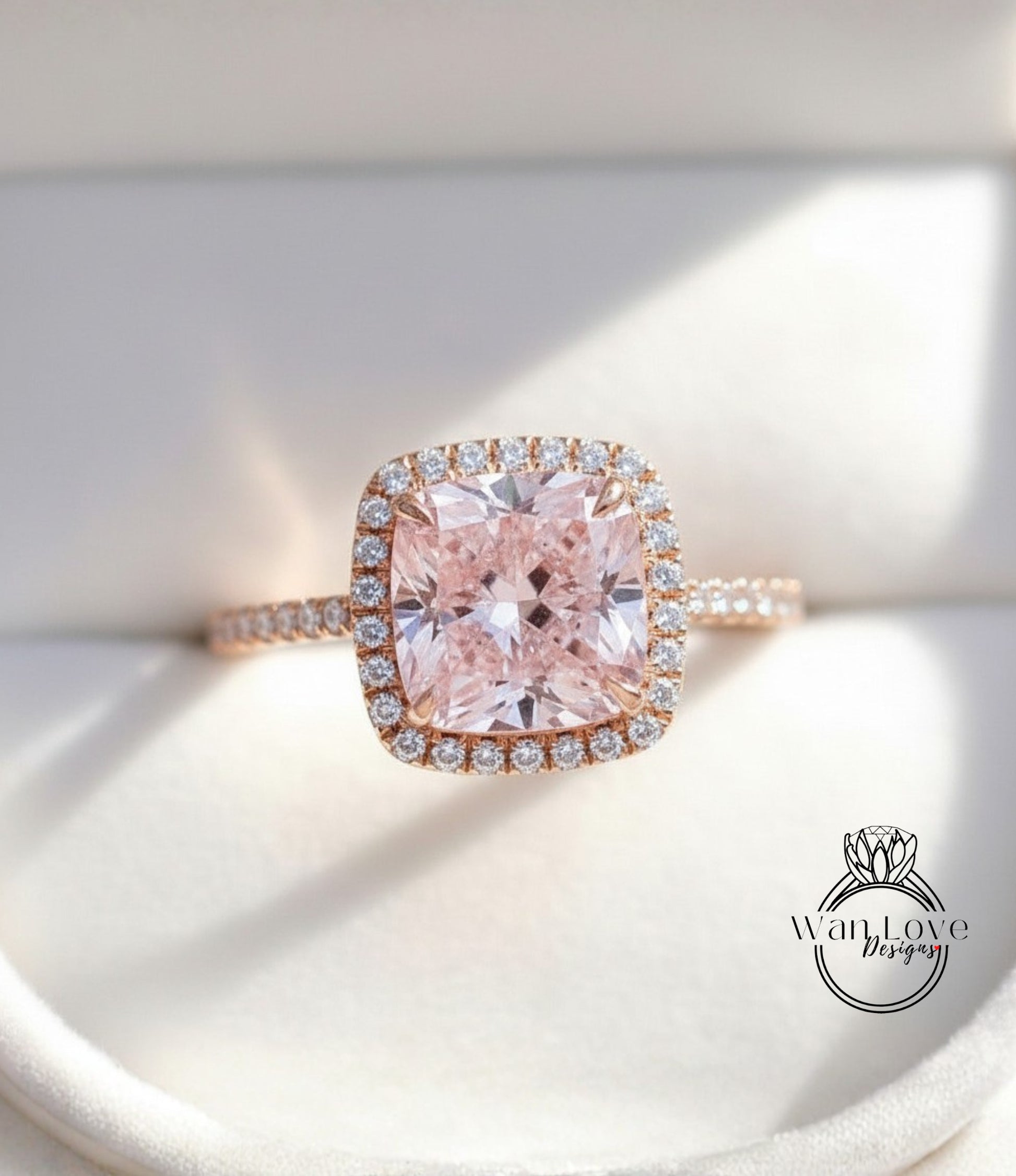 A close-up image of a beautiful pink diamond ring with a halo of smaller diamonds around the center stone.