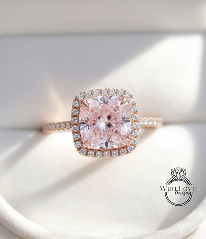 A close-up image of a beautiful pink diamond ring with a halo of smaller diamonds around the center stone.