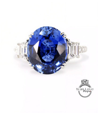 A stunning blue sapphire engagement ring with a large central stone surrounded by smaller stones on either side.