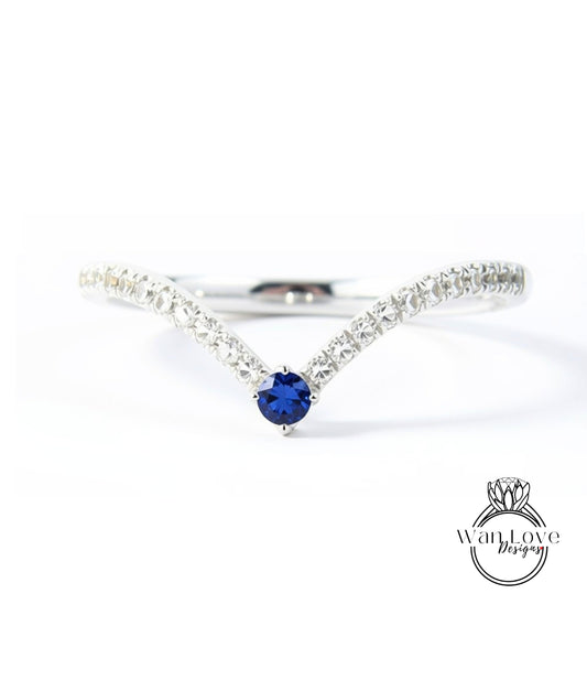 A silver ring with a blue gemstone, possibly a sapphire, at the center.