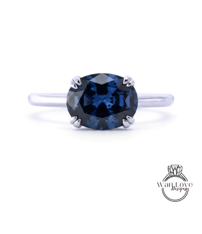 A silver ring with a large blue gemstone, likely a sapphire, as the centerpiece.