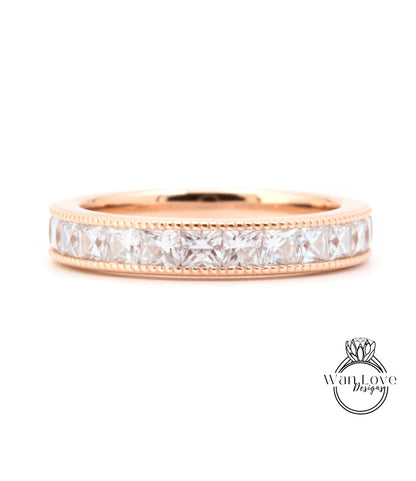A gold band ring with a row of clear gemstones, likely diamonds, set in a rose gold band.