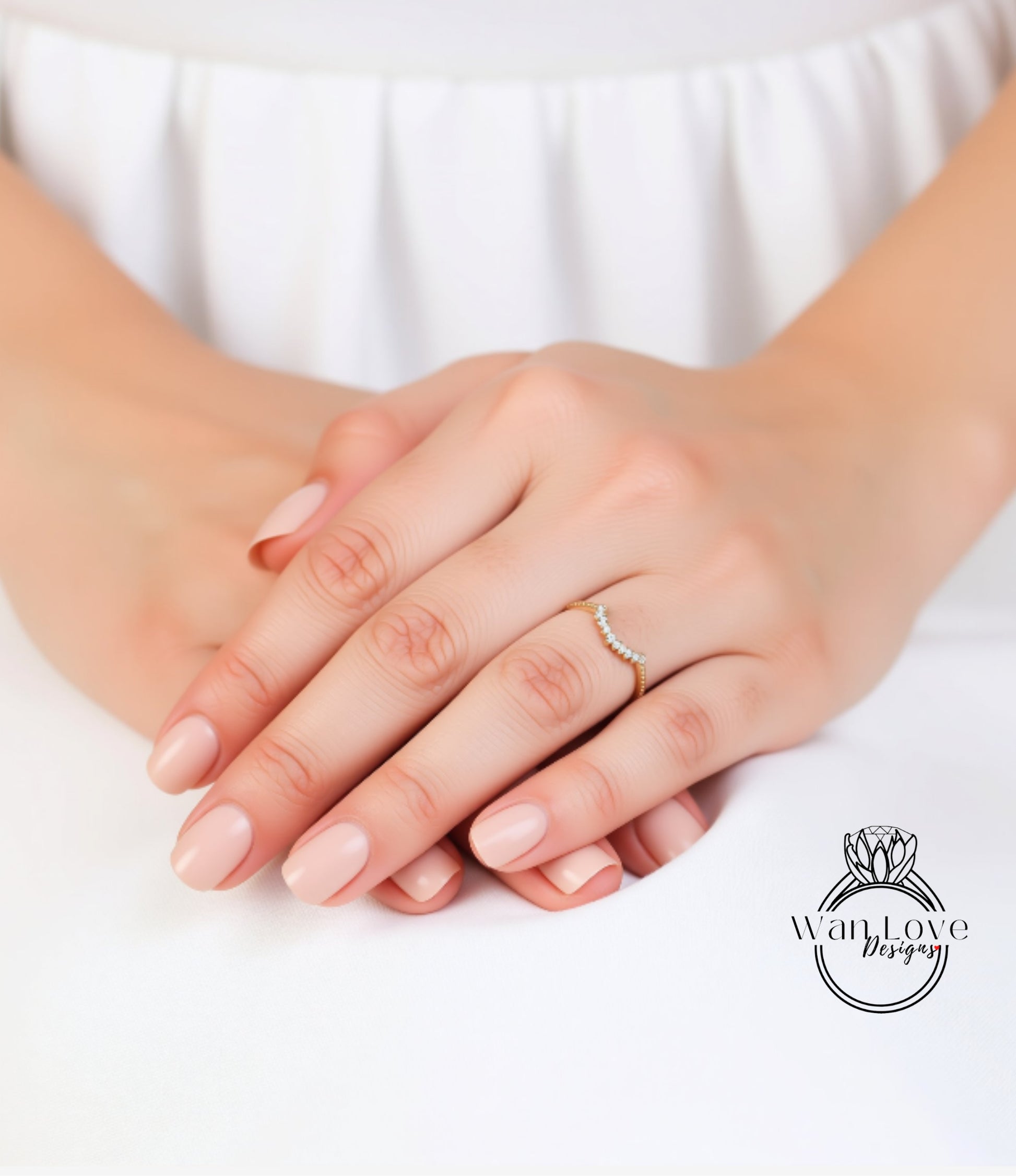 A close-up image of a person's hands with a ring on the ring finger, resting on a white surface.