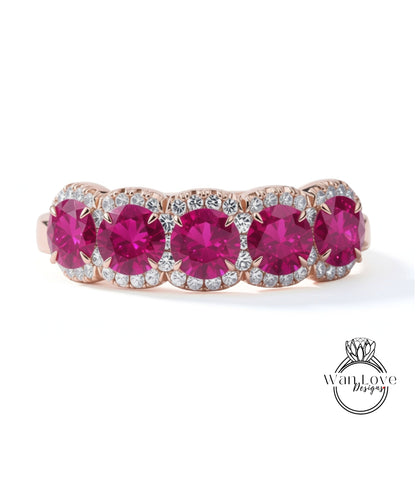 A pink and gold ring with a row of five large, round, deep red gemstones set in a halo of smaller diamonds.
