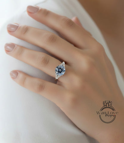 A close-up of a person's hand wearing a diamond engagement ring.