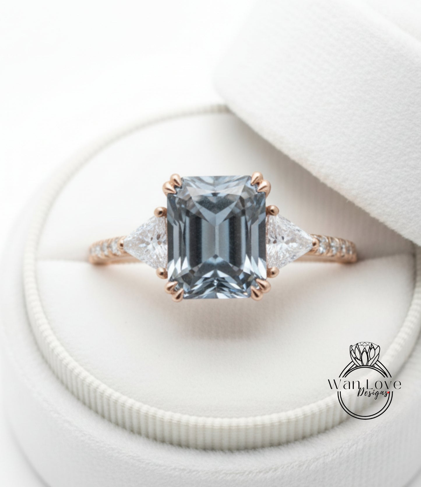 A close-up view of a beautiful engagement ring with a large blue gemstone set in a gold band, placed in a white jewelry box.