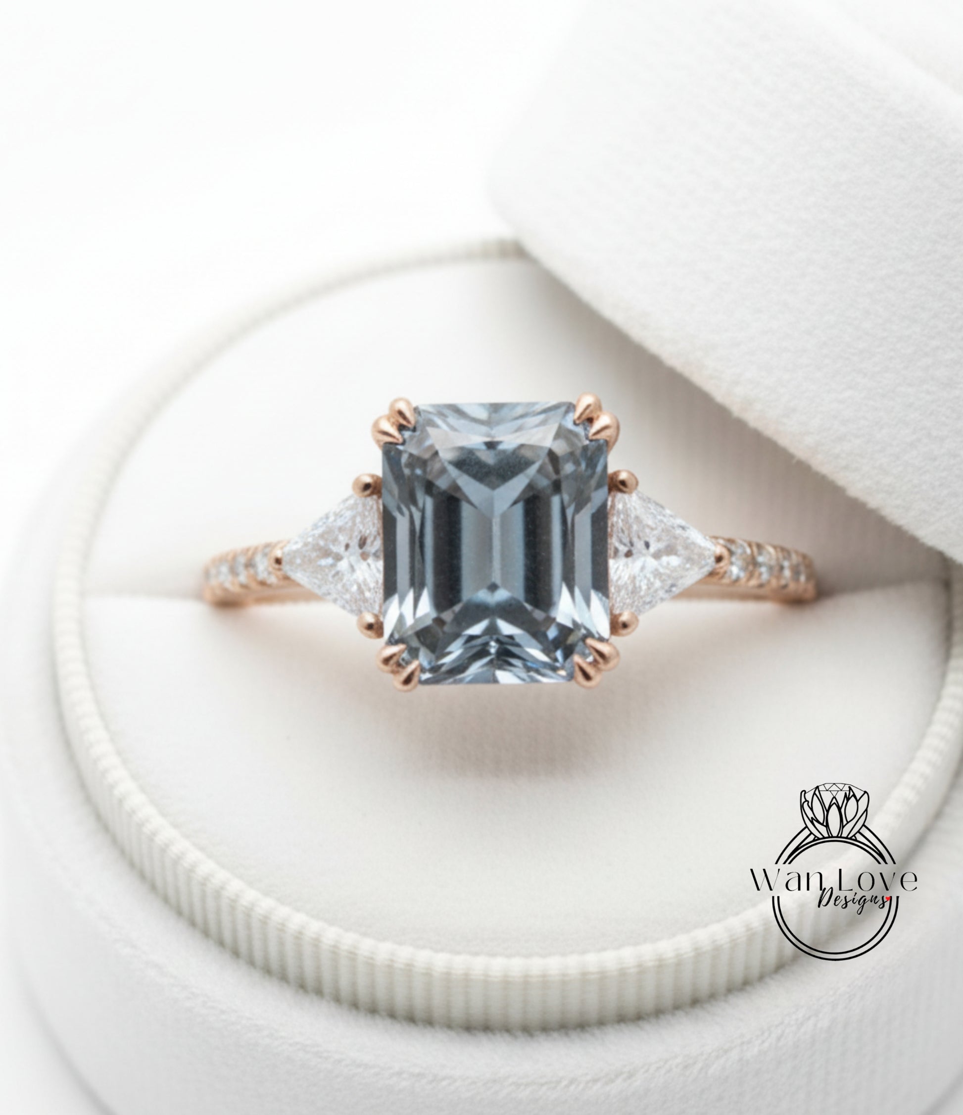 A close-up view of a beautiful engagement ring with a large blue gemstone set in a gold band, placed in a white jewelry box.