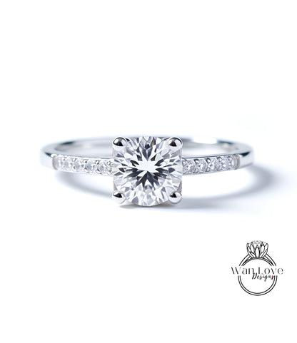 A close-up view of a diamond engagement ring with a large central diamond surrounded by smaller diamonds set in a silver band.