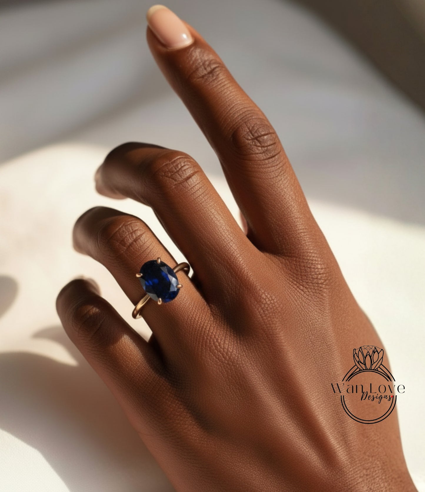 A close-up of a hand wearing a ring with a large blue gemstone.