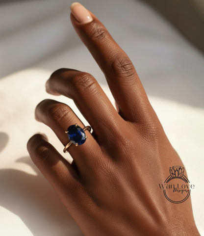 A close-up of a hand wearing a ring with a large blue gemstone.
