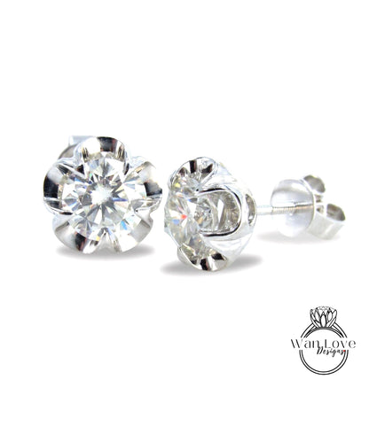 A pair of elegant diamond stud earrings with a clear gemstone set in a silver metal earring back.