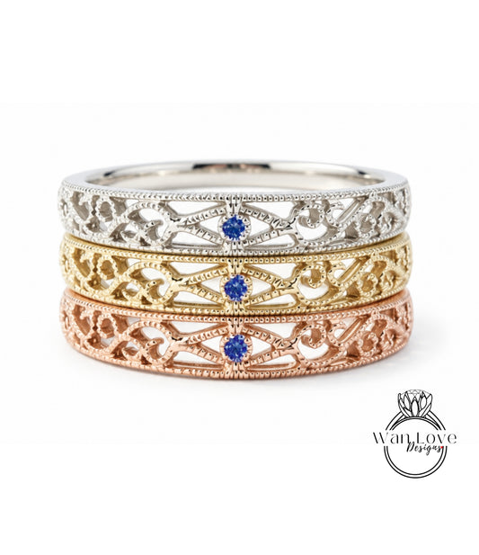 A three-tone ring with intricate designs and a blue gemstone in the center.