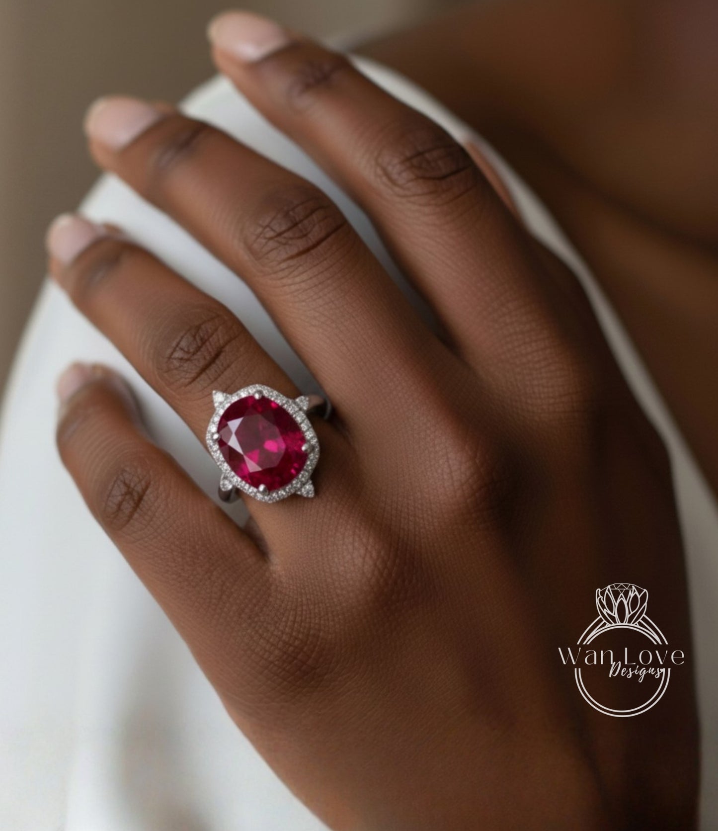 A close-up of a hand wearing a large, red gemstone ring with a halo of smaller diamonds around it.