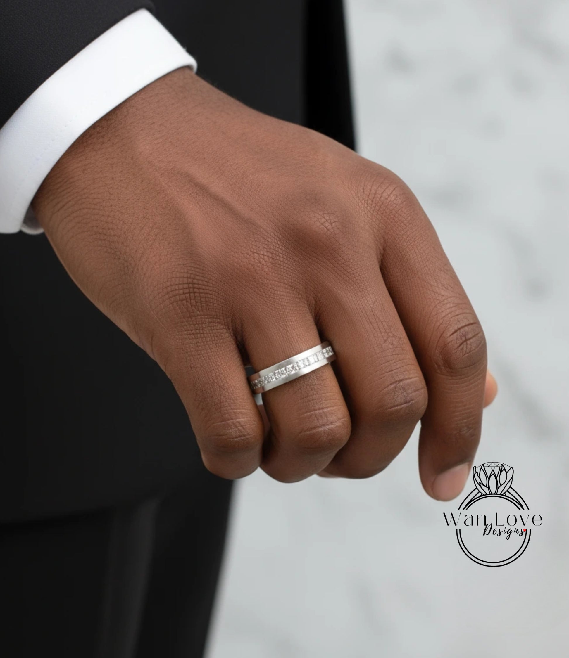 A close-up of a person's hand wearing a silver ring on the ring finger.