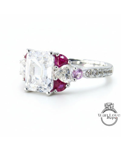 A close-up image of a diamond engagement ring with a large central diamond surrounded by smaller diamonds and gemstones in various colors, including clear, pink, and purple.