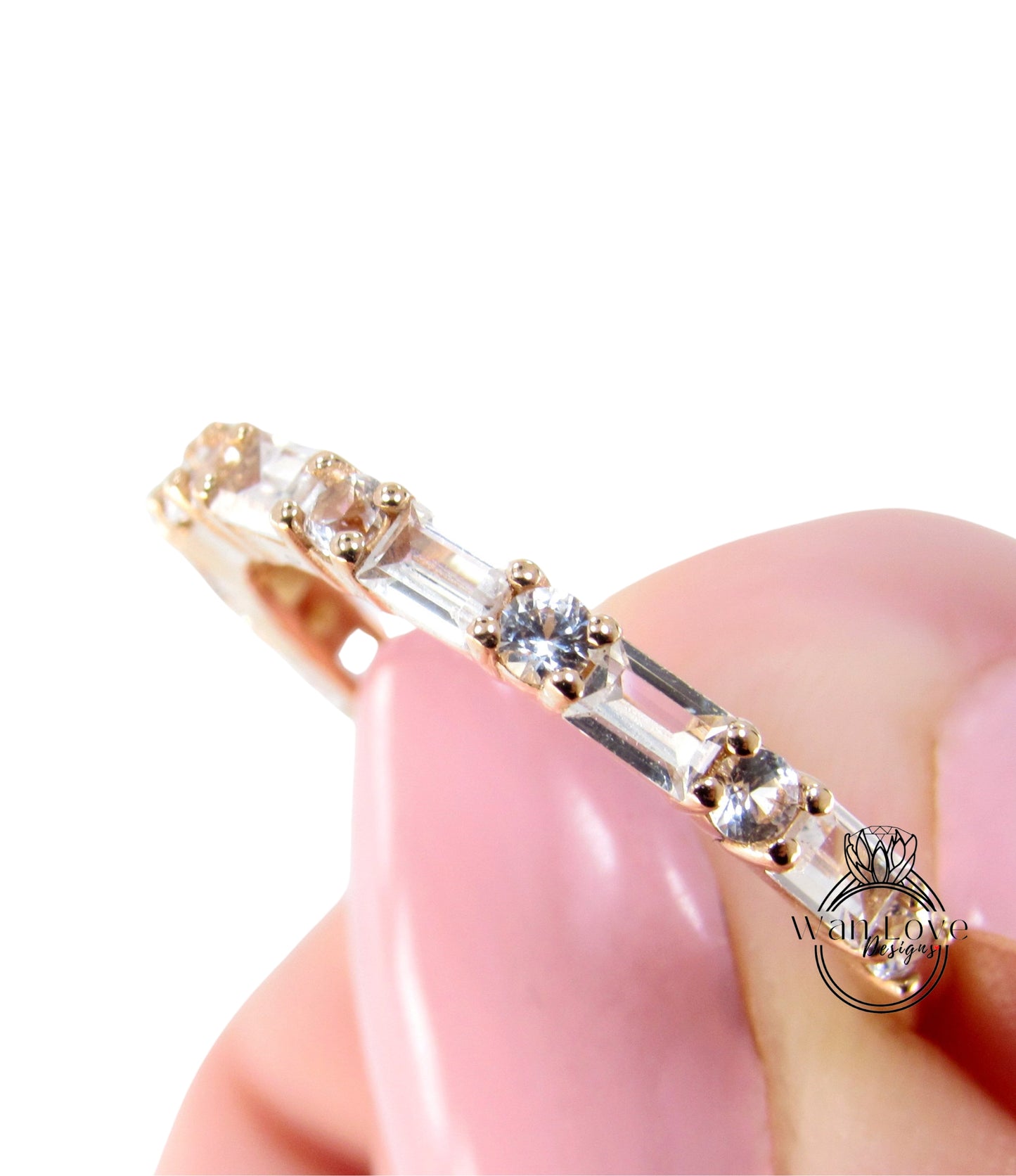 A close-up of a person's hand holding a delicate ring with a row of small diamonds on it.