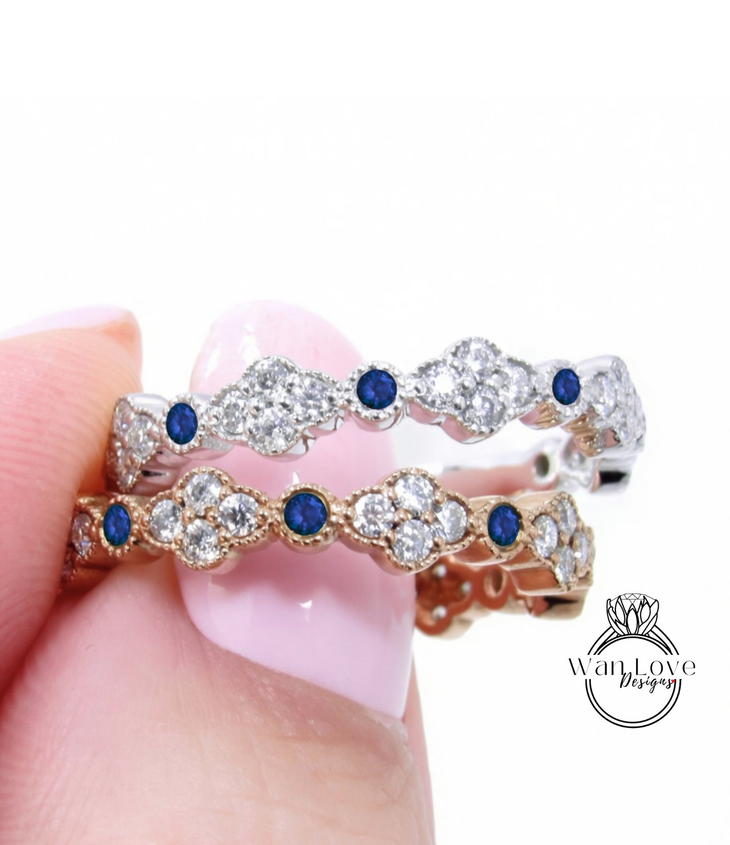 A close-up of a person's hand holding a gold and silver ring with blue gemstones.