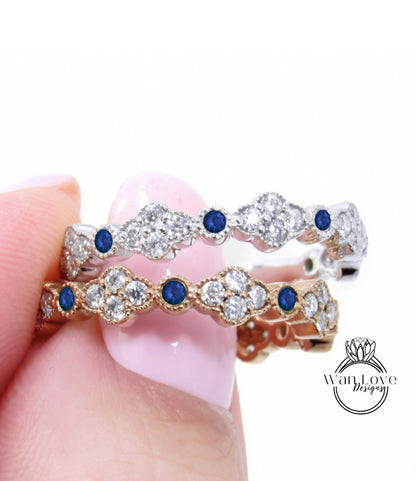 A close-up of a person's hand holding a gold and silver ring with blue gemstones.