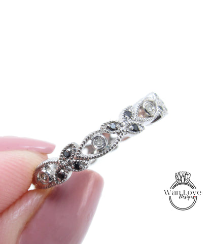 A close-up image of a person's hand holding a silver ring adorned with black gemstones.