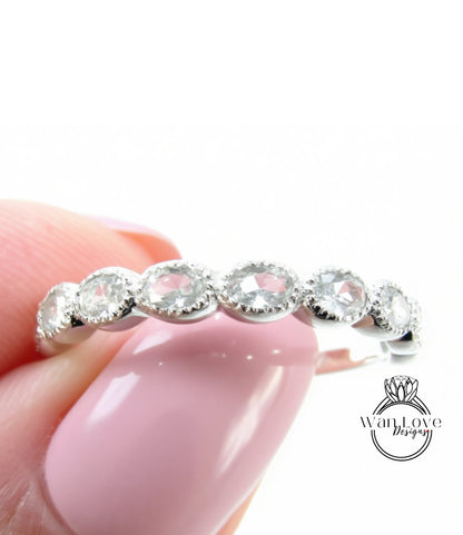 A close-up of a person's hand holding a ring with a row of clear gemstones on it.