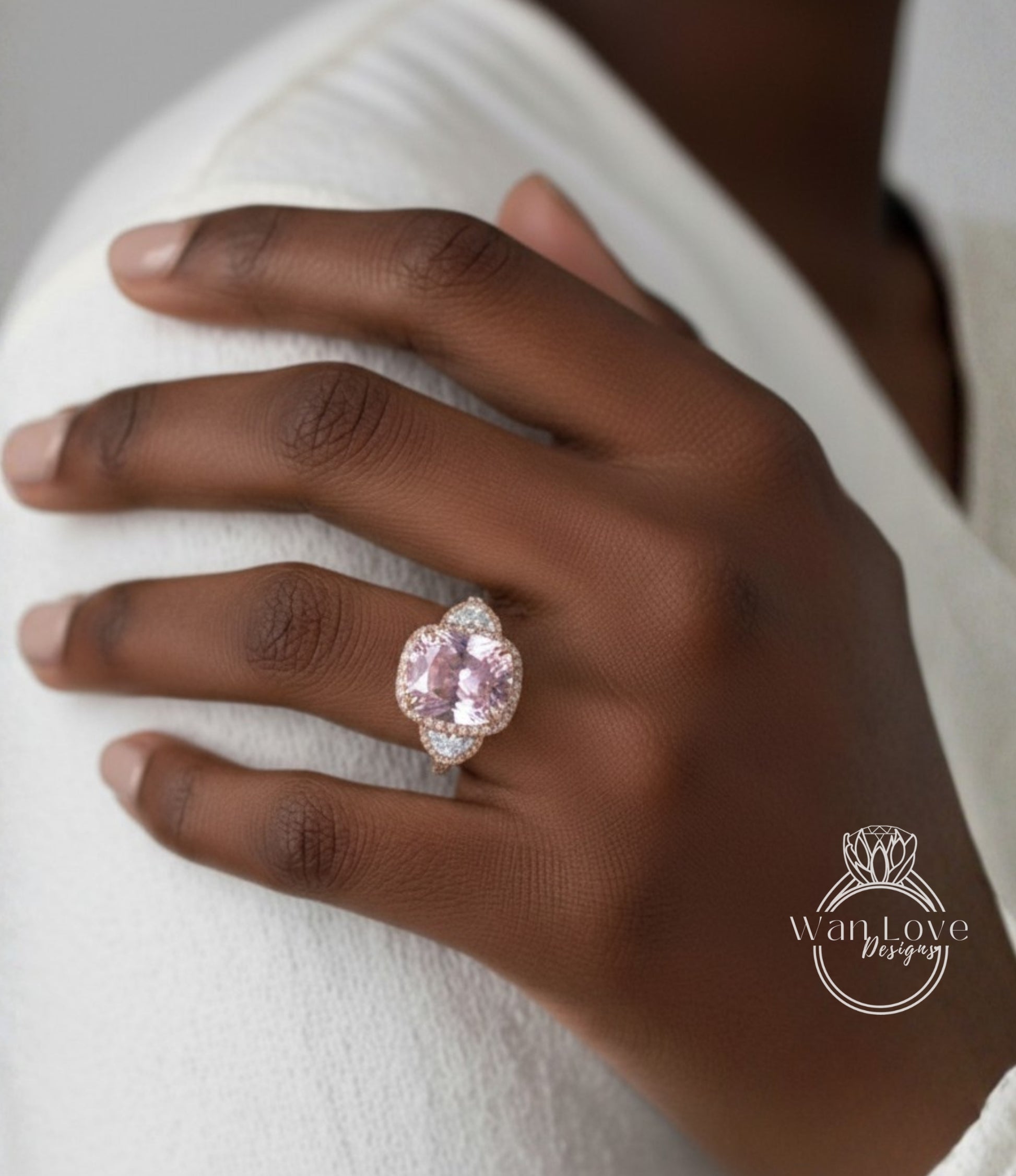 A close-up of a hand wearing a large, ornate ring with a pink gemstone.