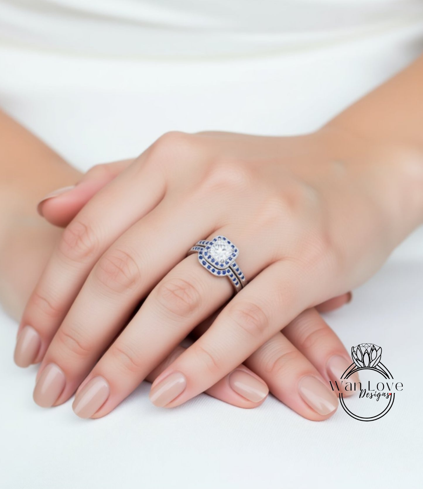 A close-up image of a person's hand wearing a diamond engagement ring with a large central diamond surrounded by smaller diamonds.