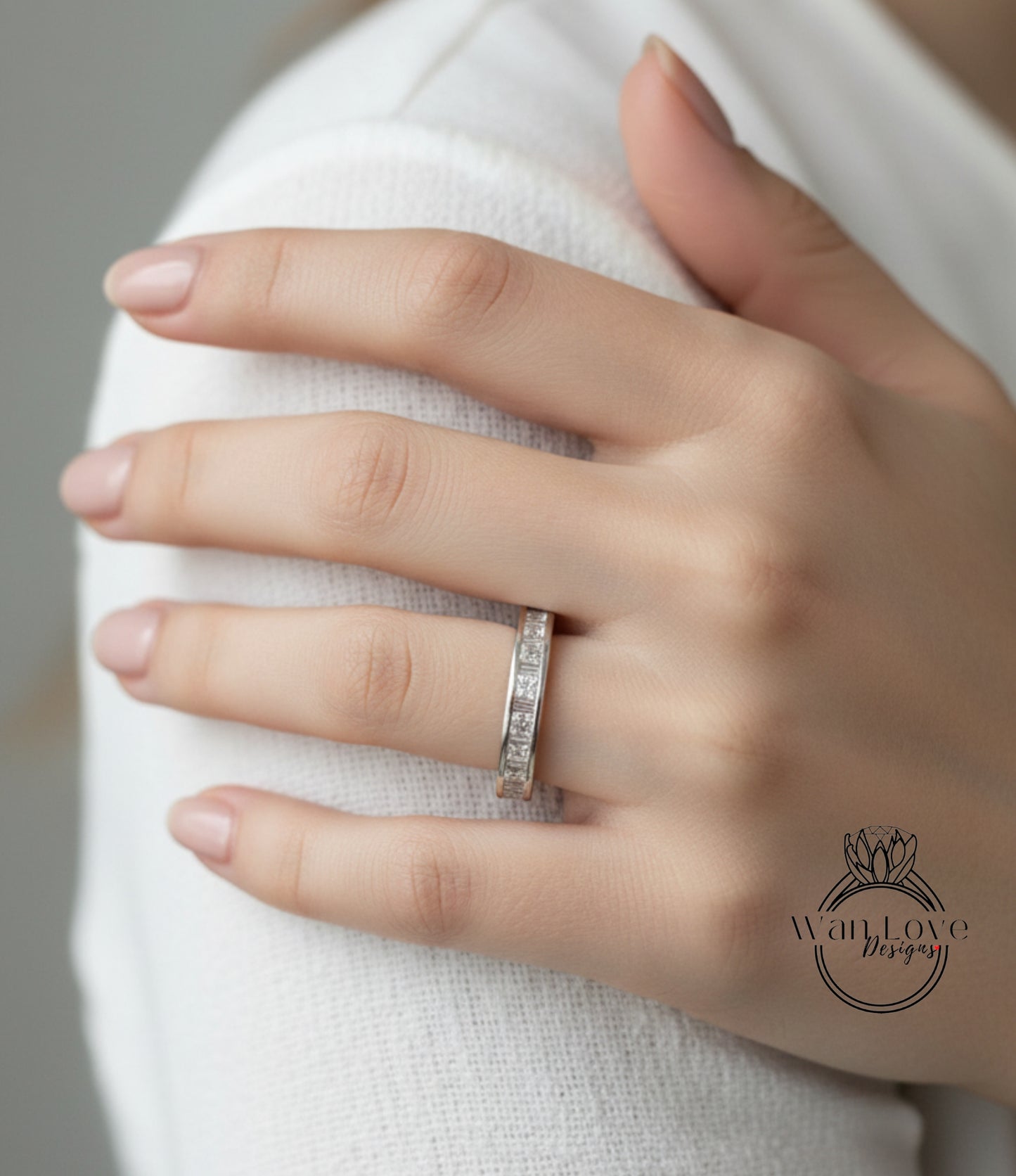 A close-up of a person's hand wearing a diamond ring on the ring finger.