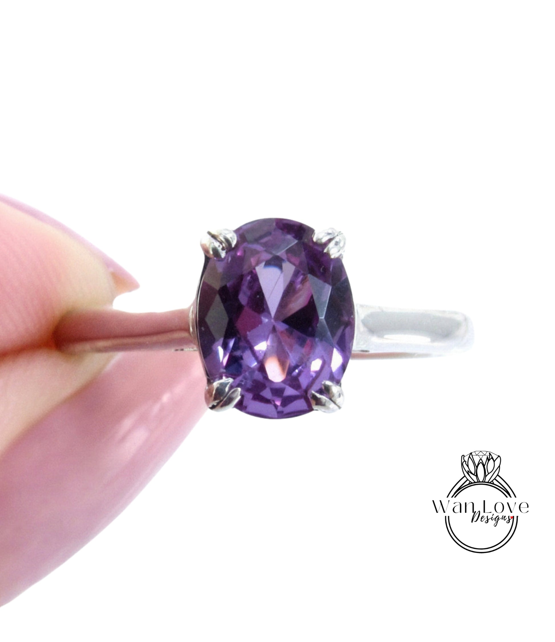 A close-up image of a person's hand holding a ring with a large, oval-shaped purple gemstone.