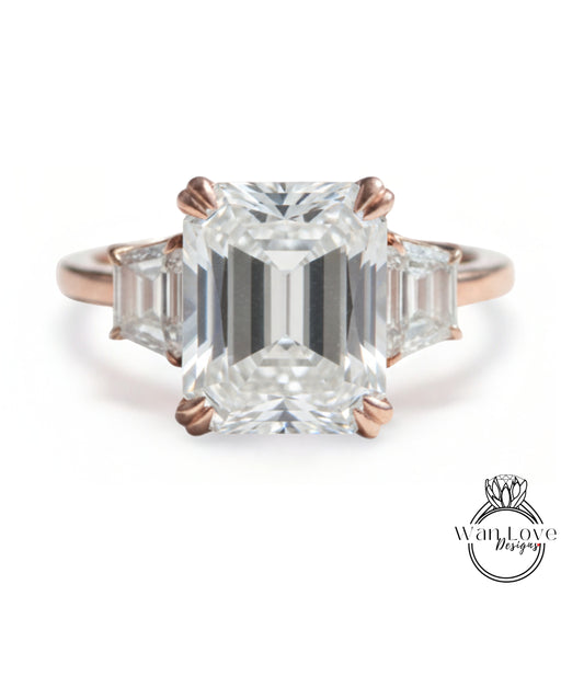 A large, clear gemstone engagement ring with a prominent central diamond surrounded by smaller diamonds on either side.