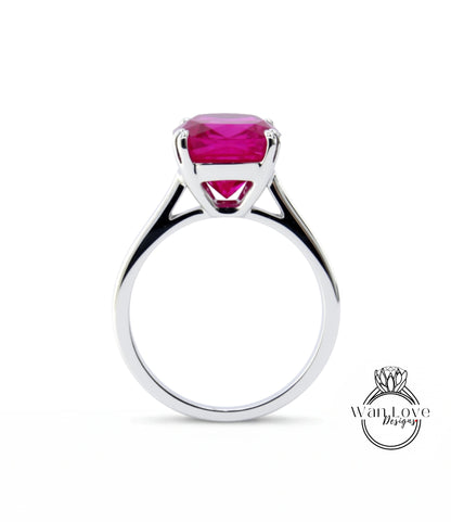 A silver ring with a large, bright pink gemstone set in the center.