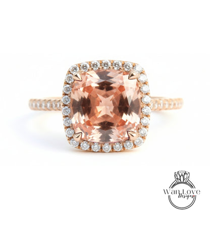 A large, peach-colored gemstone ring with a halo of smaller diamonds around the center stone.