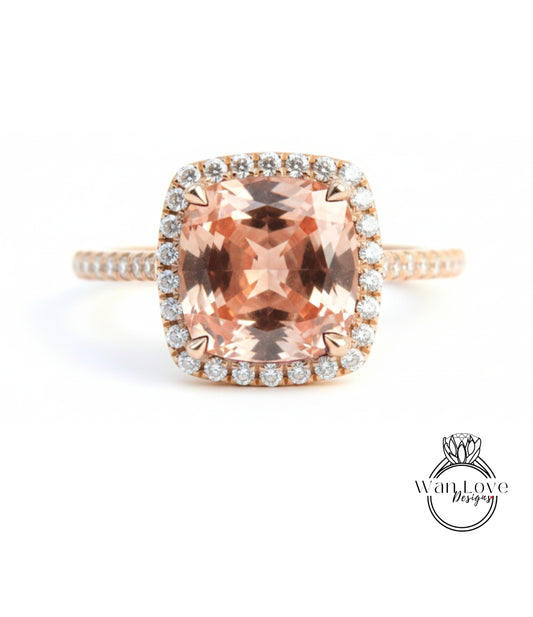 A large, peach-colored gemstone ring with a halo of smaller diamonds around the center stone.