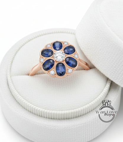 A gold ring with a large blue gemstone set in the center, placed in a white jewelry box.
