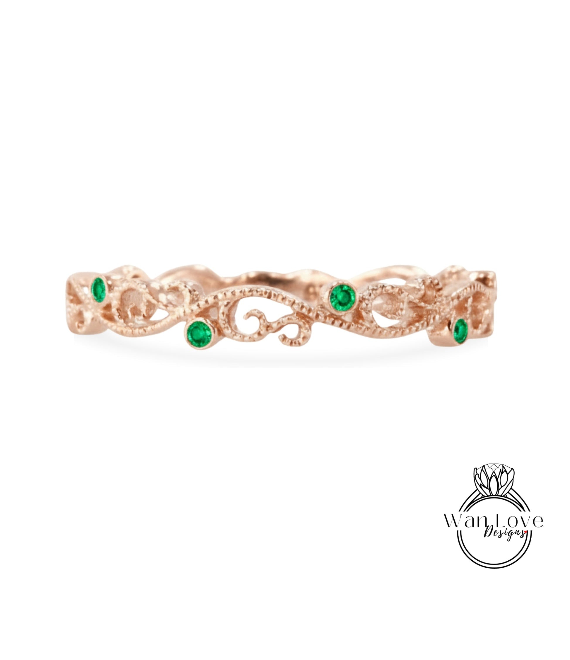 A rose gold ring with a decorative floral design and green gemstones.