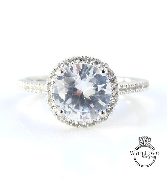 A close-up image of a diamond ring with a large, clear gemstone set in a halo of smaller diamonds.
