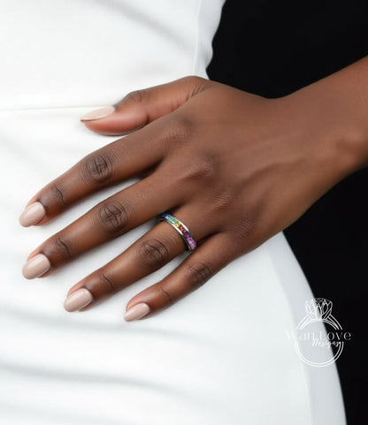 A close-up of a hand wearing a ring with a colorful band, resting on a white surface.