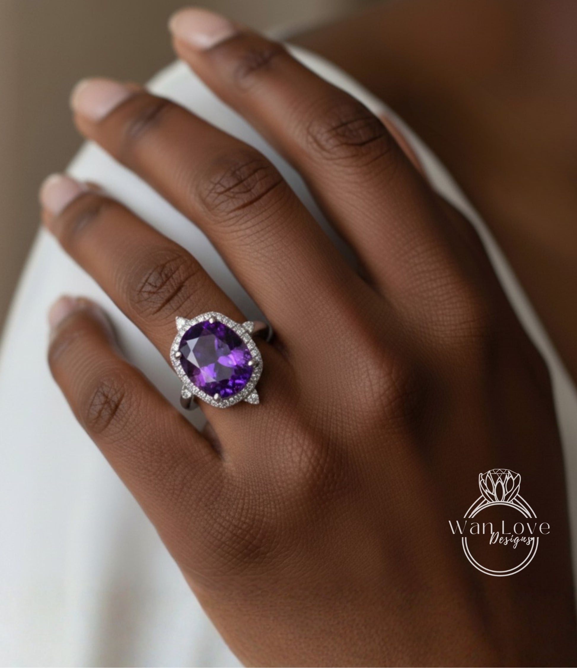 A close-up of a hand wearing a large, oval-shaped purple gemstone ring with a halo of smaller diamonds around it.