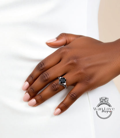 A close-up of a hand wearing a ring with a large black gemstone, resting on a white surface.