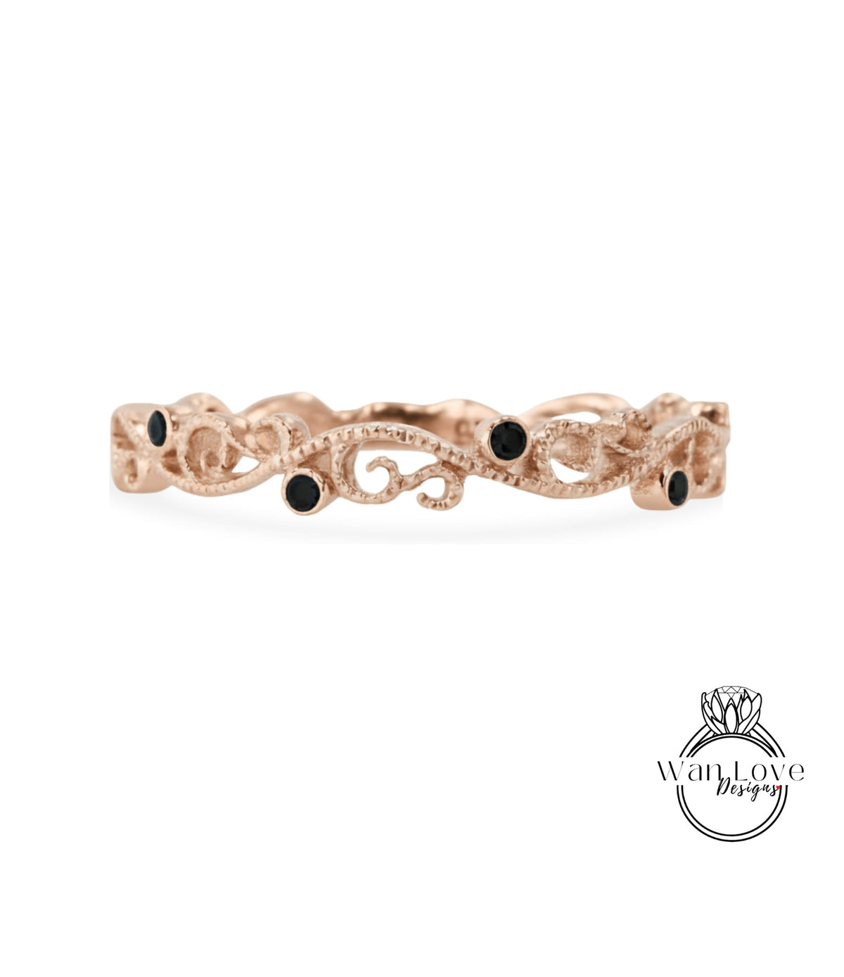A rose gold ring with a decorative scroll design and small black gemstones.