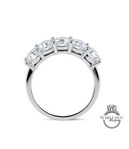 A silver ring with a row of five clear gemstones set in the band.