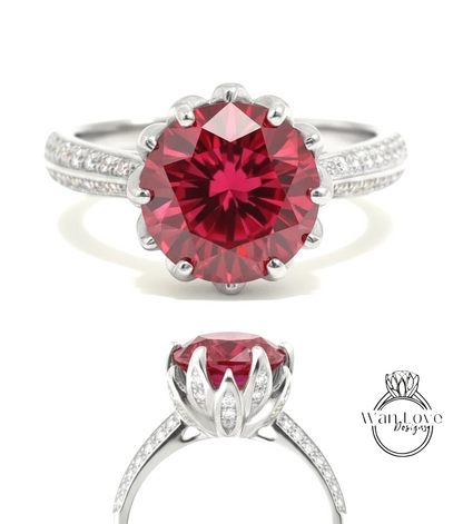A stunning red gemstone ring with a large, round center stone surrounded by smaller diamonds. The ring is set in a silver band with a scalloped edge, and the image showcases the ring from various angles, highlighting its intricate design and vibrant color.