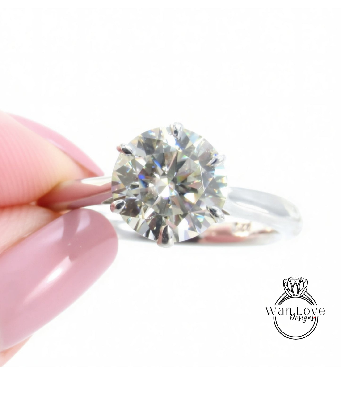 A close-up of a person's hand holding a diamond engagement ring, with the ring's diamond visible.