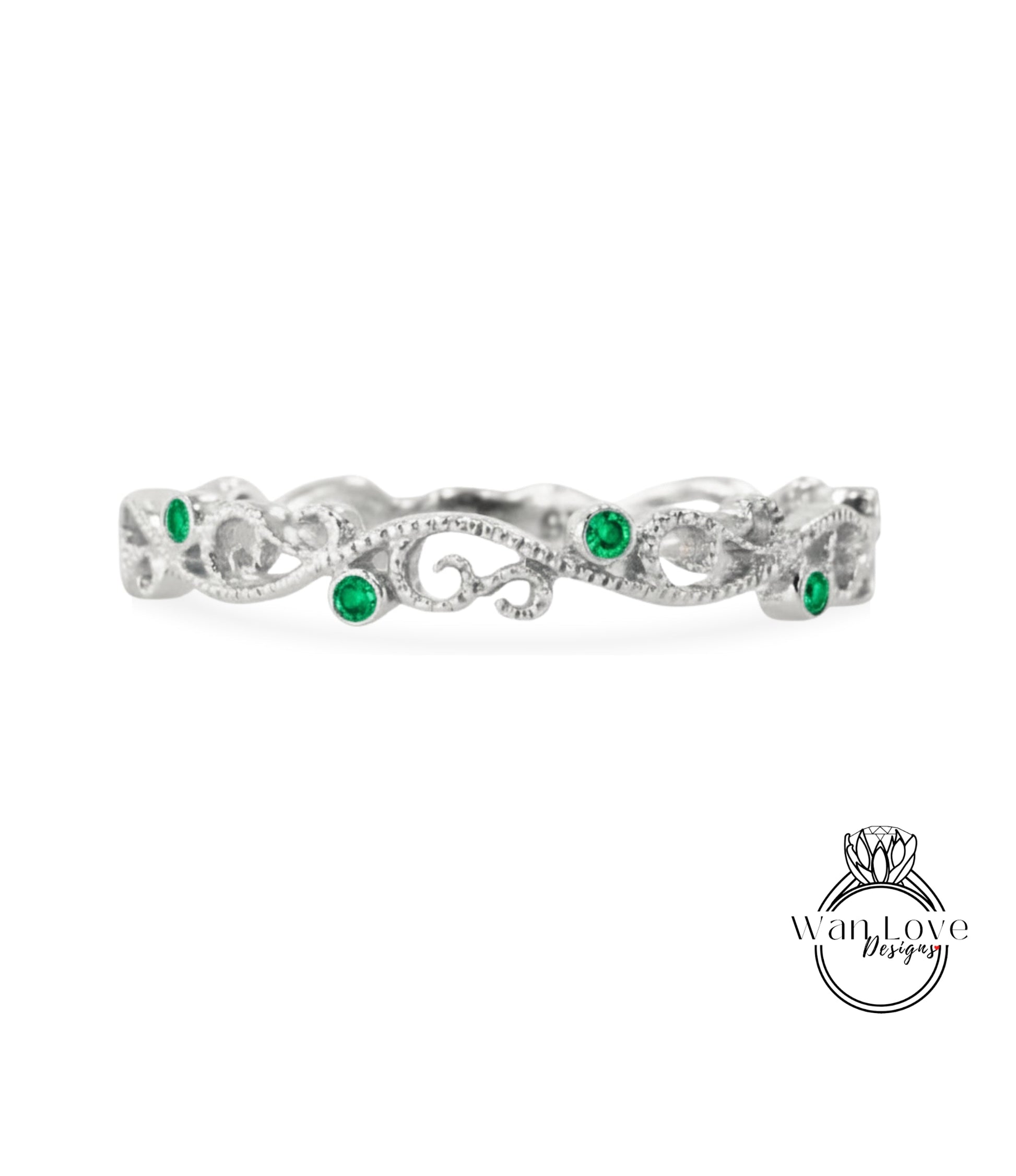 A silver ring with a decorative design and green gemstones.