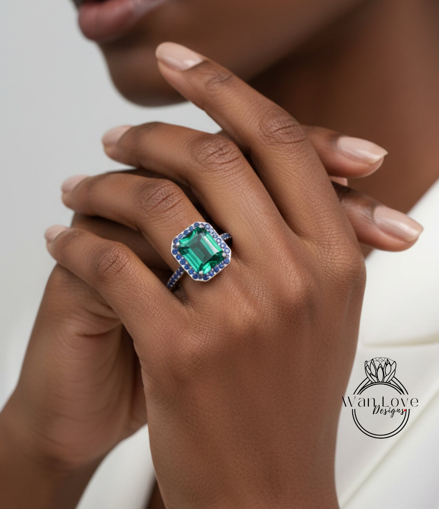 A close-up of a person's hand wearing a large, green gemstone ring with blue accents.