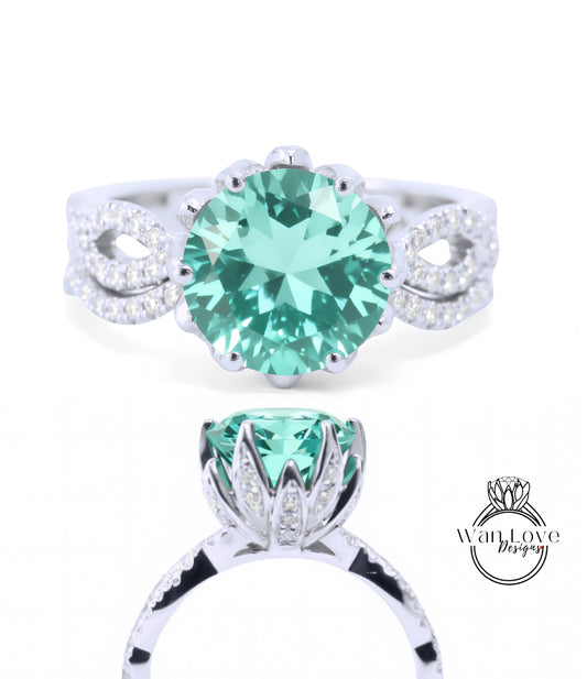 A silver ring with a large, round, green gemstone at the center. The ring has a delicate, flower-like design around the gemstone.