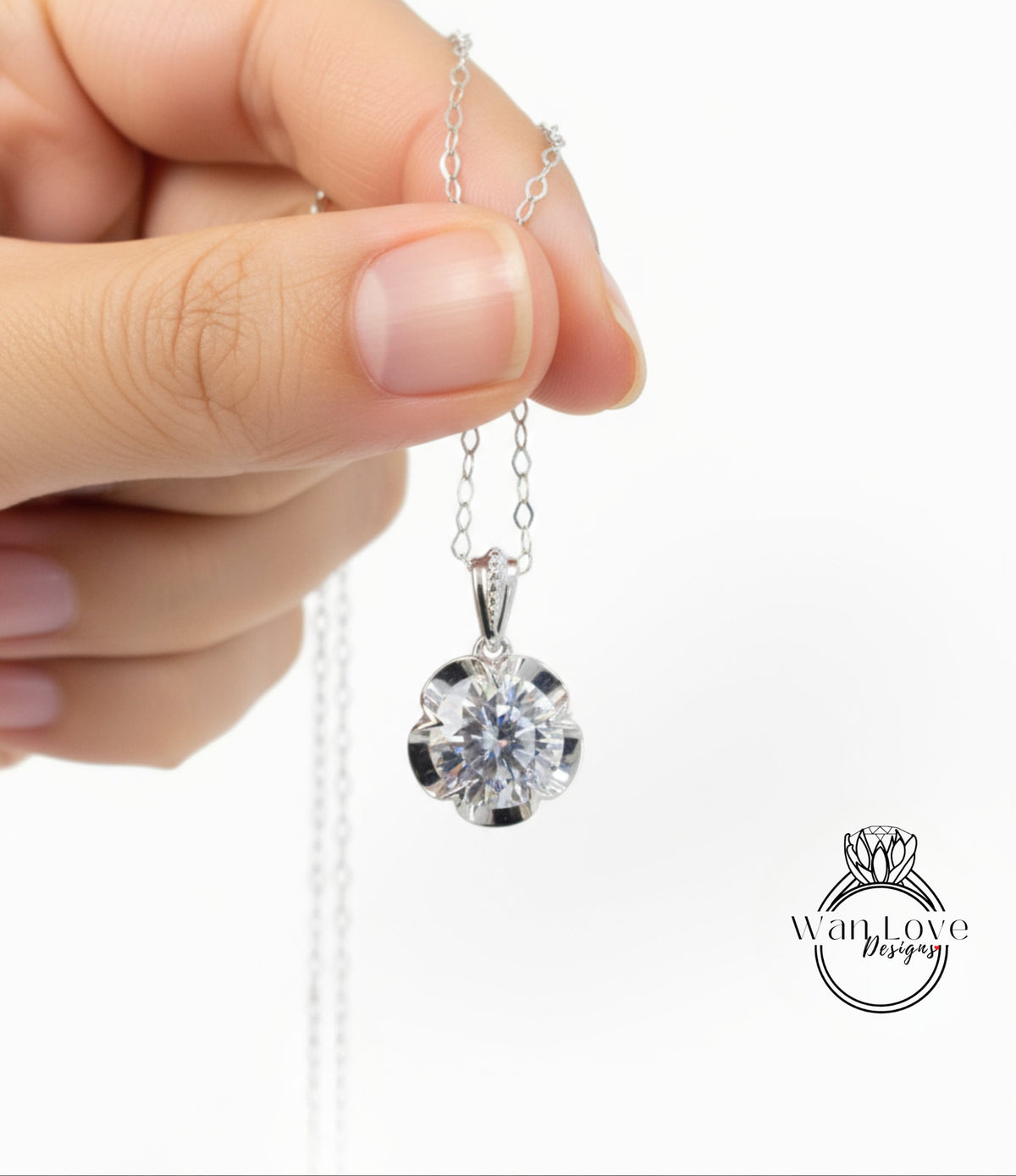 A hand holding a silver necklace with a large, clear gemstone pendant.