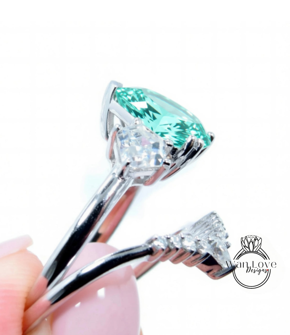 A close-up view of a silver ring with a large, green gemstone set in it, held by a person's hand.
