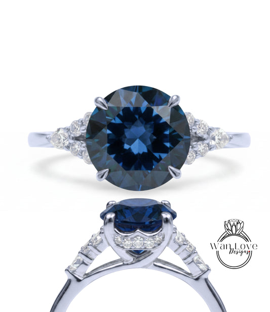 A stunning blue diamond engagement ring with a large central diamond surrounded by smaller diamonds on either side. The ring is set in a silver band, and the image showcases the intricate design and craftsmanship of the piece.