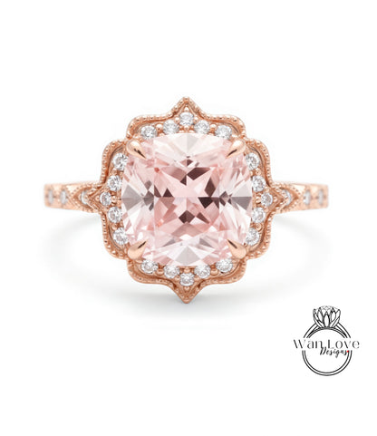 A beautiful pink gemstone ring with a large central gemstone surrounded by smaller diamonds set in an ornate, scalloped design.