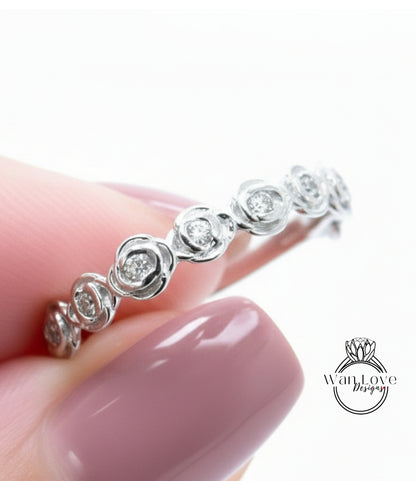 A close-up of a person's hand wearing a silver ring with a row of small diamonds on it.